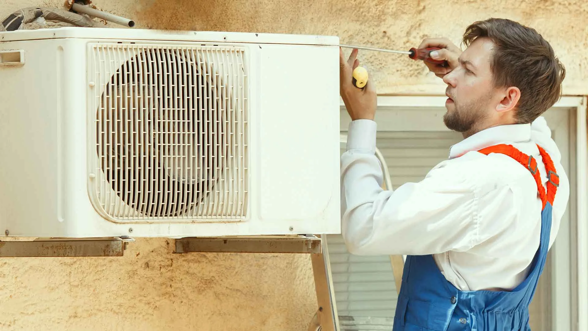 فني صيانة كلفينيتور يقوم بإصلاح التكييف داخل منزل العميل باستخدام أدوات حديثة